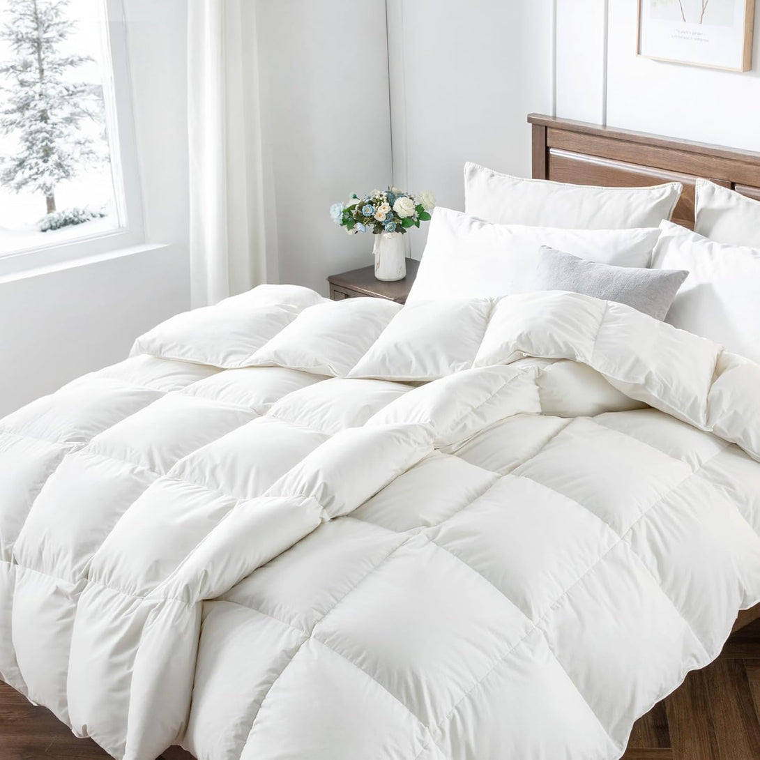 A bed with a BRIT DIAMOND Premium Hotel Quality Duvet Deep Sleep Quilt sits beside a wooden nightstand holding flowers, while a snowy landscape can be seen through the window.