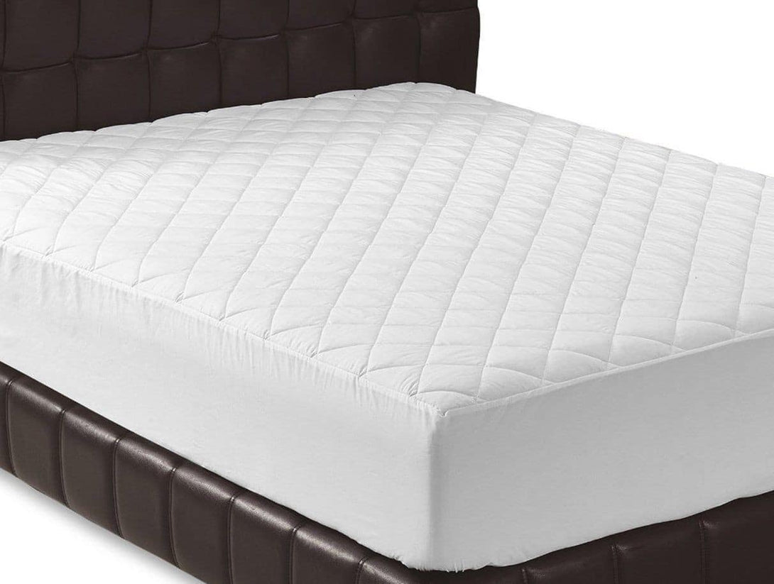 The BRIT DIAMOND Quilted Mattress Protector, 100% cotton and anti-allergic, covers a mattress on a dark upholstered bed. Featuring a diamond pattern and machine washable design, it fits UK beds in all sizes with 30cm & 40cm extra deep options in a plain white room.