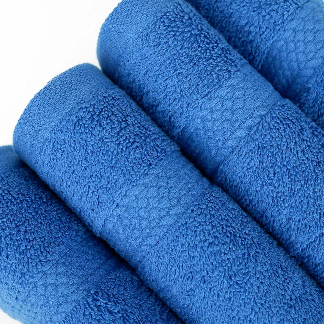 Four soft, 100% cotton BRIT DIAMOND bath towels in blue, from the Bath Towels Pack of 2 or 4, are neatly rolled side by side on a white surface, highlighting their absorbent texture and patterned bands.