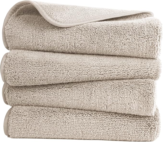A set of four beige BRIT DIAMOND 100% cotton hand towels, soft and absorbent, with one towel partially unfolded on top to reveal their plush quick-dry texture.