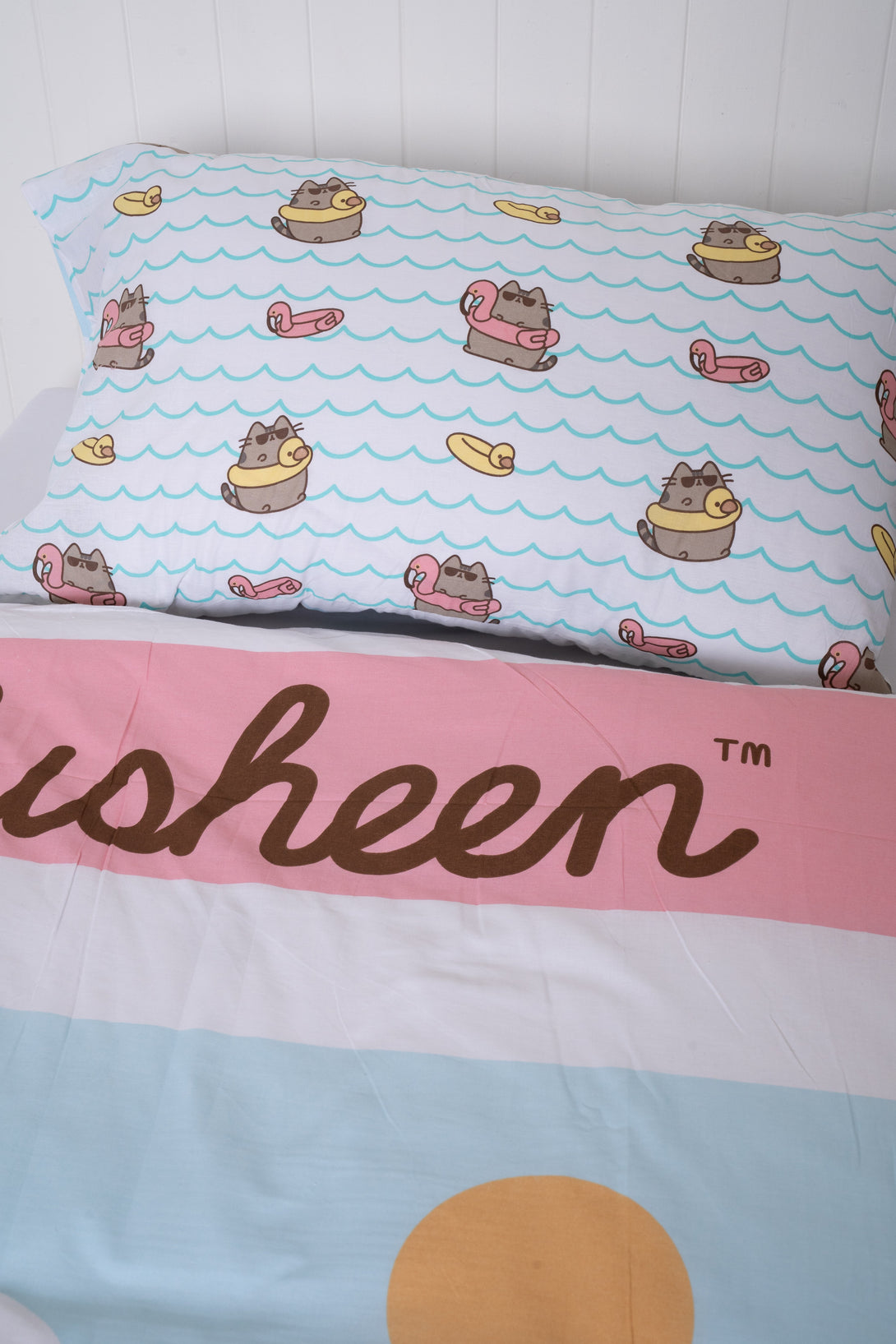 The BRIT DIAMOND Kids Pusheen Reversible Duvet Cover Set is a cute, cosy, double-sided bedding set featuring cartoon cats in sunglasses on inflatables, with “Pusheen™” text on pastel stripes and a yellow circle accent.