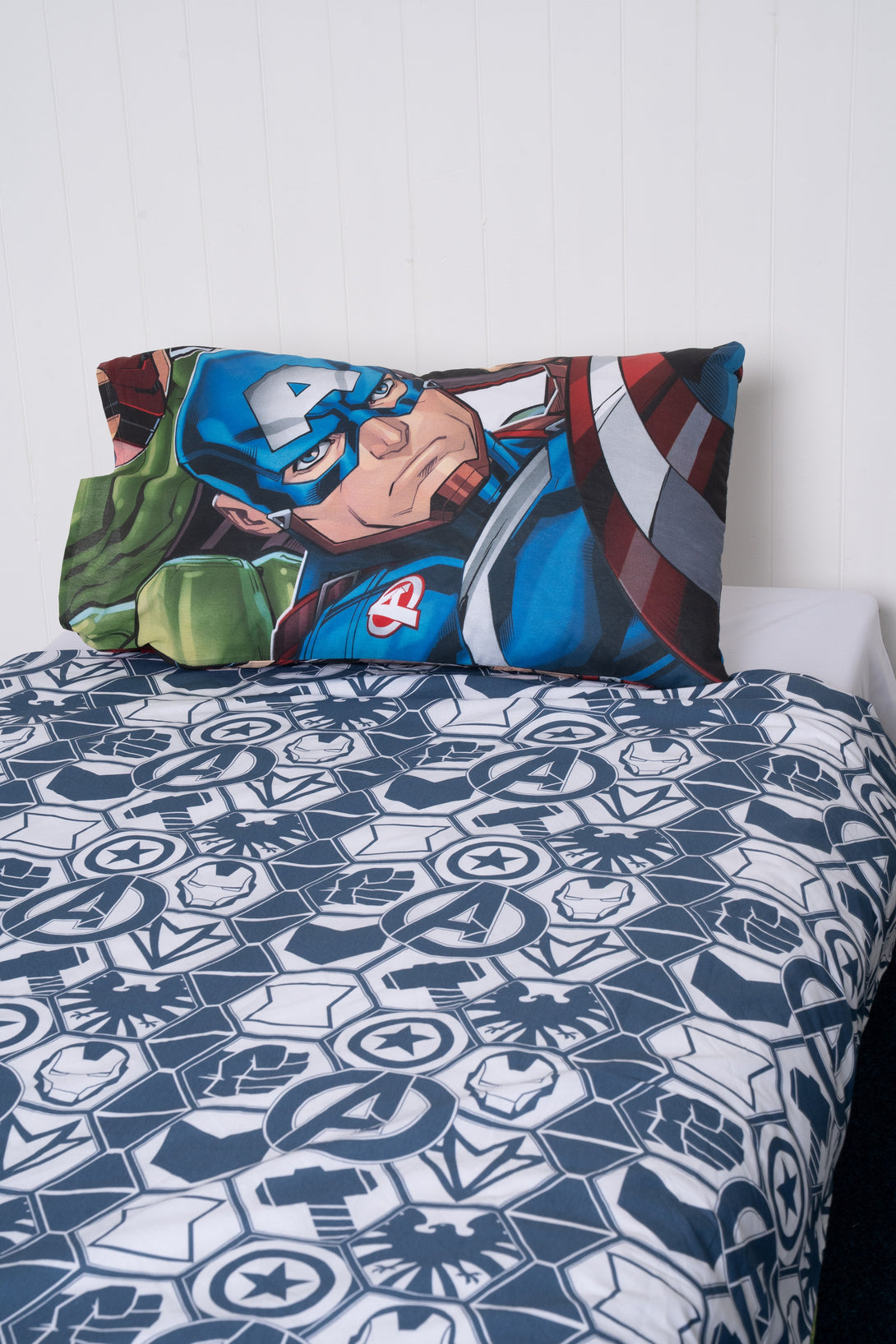 A neatly made bed with the BRIT DIAMOND Marvel Avengers Reversible Duvet Cover Set—action-packed superhero bedding featuring blue-white geometric patterns and Marvel logos—is perfect for fans seeking bold, fun bedroom decor.