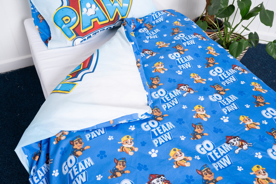 The BRIT DIAMOND Kids Paw Patrol Reversible Duvet Cover Set is a blue 2-in-1 adventure bedding for little heroes, featuring GO TEAM PAW! and a matching pillowcase, shown with a green potted plant by the bed.