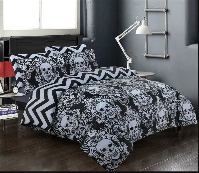 A modern bedroom featuring the BRIT DIAMOND Reversible Duvet Cover Set, 100% Cotton 200TC, with a skull print, chevron pillowcases, a red lamp on a nightstand, white desk lamp, and ladder-style wall decor against gray walls.