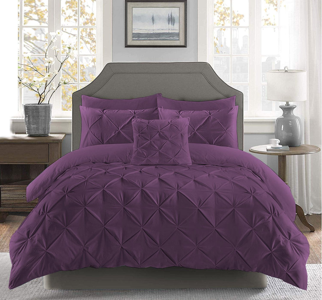 A bright bedroom features a gray upholstered headboard and side tables, with a neatly made bed dressed in the BRIT DIAMOND Pintuck Duvet Set, 100% Egyptian Cotton, in purple, and matching pillows showcasing elegant pintuck detailing.