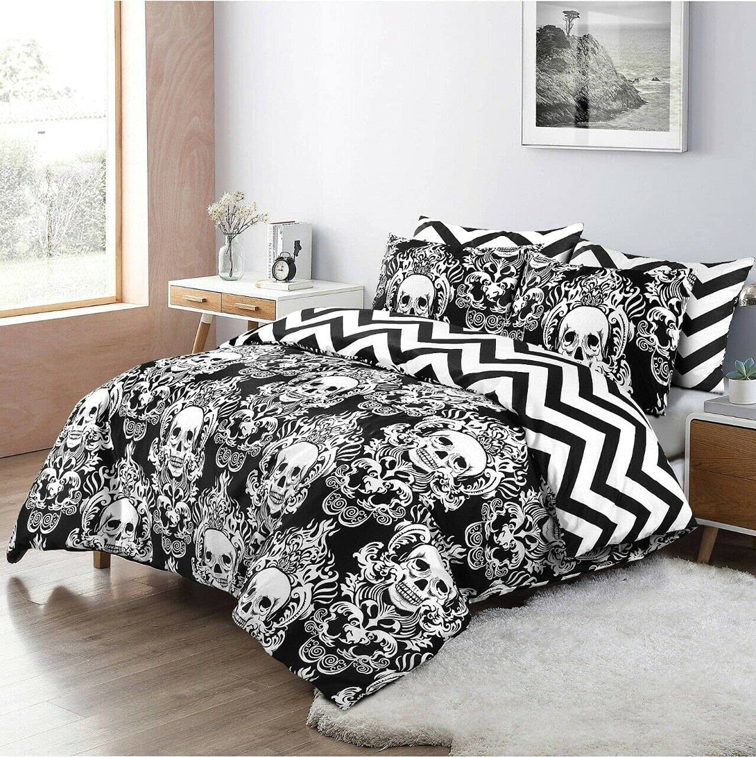 A bedroom features a BRIT DIAMOND Reversible Duvet Cover Set in 100% cotton with black-and-white skull, flame, and chevron patterns. A window, wooden nightstand with plant and books, and framed art above the bed complete the scene.