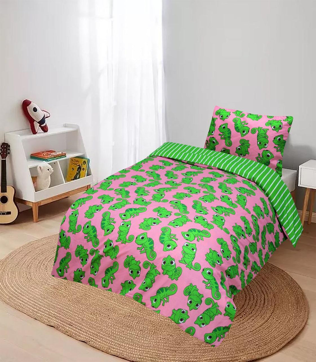 A childs room features a bed with the BRIT DIAMOND Kids Tangled Pascal Pink Rotary Reversible Duvet Cover Set – Magical Princess Bedding, showing playful chameleons, plus toys, a guitar, and a round rug—great for Disney bedding fans.