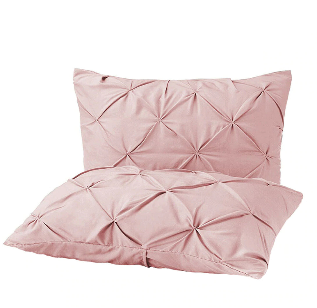 Two light pink BRIT DIAMOND Pintuck Duvet Set pillows, made from 100% Egyptian cotton, feature a pleated geometric design and are stacked against a white background. Available in Single, Double, King & Super King sizes.