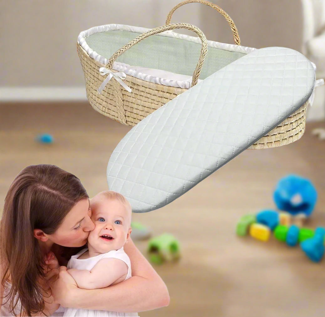 A BRIT DIAMOND Premium Baby Moses Basket Foam Mattress—soft, breathable, and safe for newborns—rests in a woven bassinet with handles. In front, a woman kisses her smiling baby dressed in white.