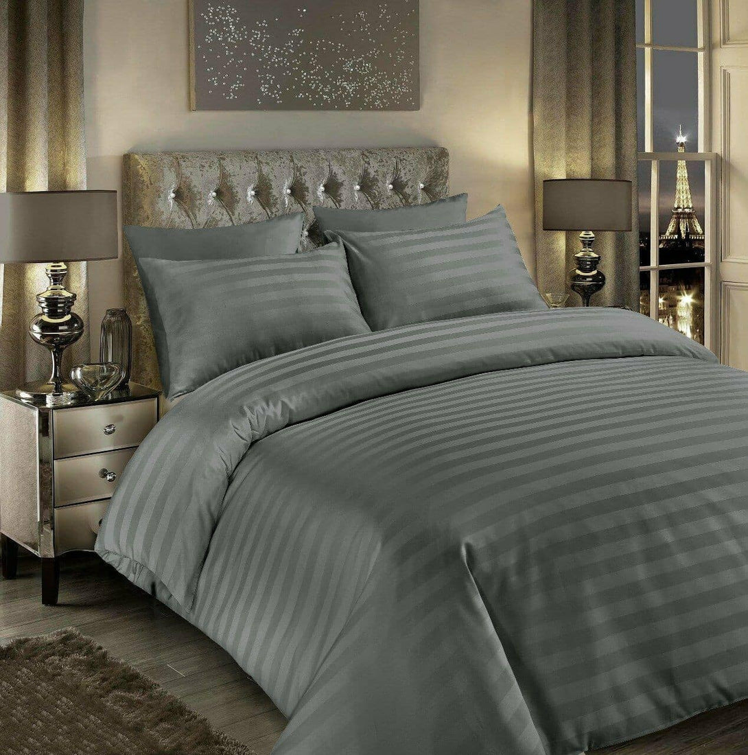 A modern bedroom showcases a neatly made bed with the BRIT DIAMOND Luxury 400 Thread Count Satin Stripe Duvet Set, crafted from 100% Egyptian cotton, plus silver lamps, mirrored nightstands, and an Eiffel Tower view through the window.