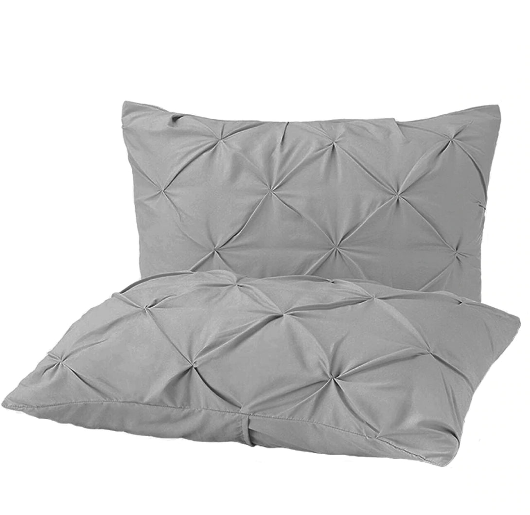 Two light gray BRIT DIAMOND pillows from the Pintuck Duvet Set, crafted from 100% Egyptian cotton, feature a ruched pintuck design for a textured, elegant look—one pillow upright and one lying flat.